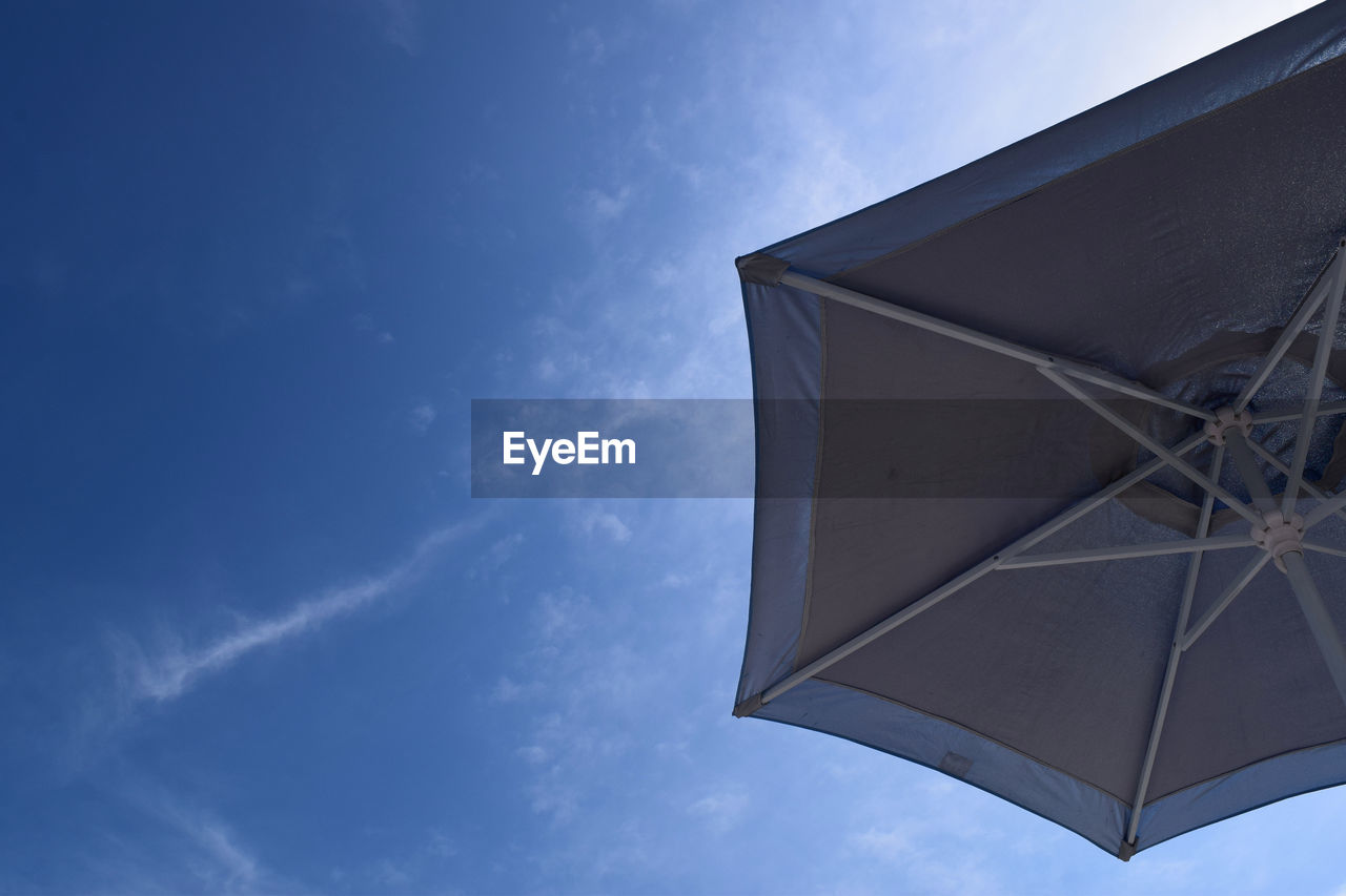 Low angle view of parasol against blue sky
