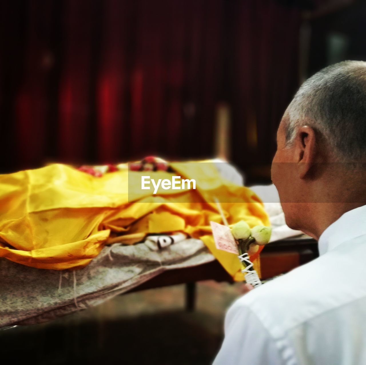 Close-up of man holding offerings in front of dead person