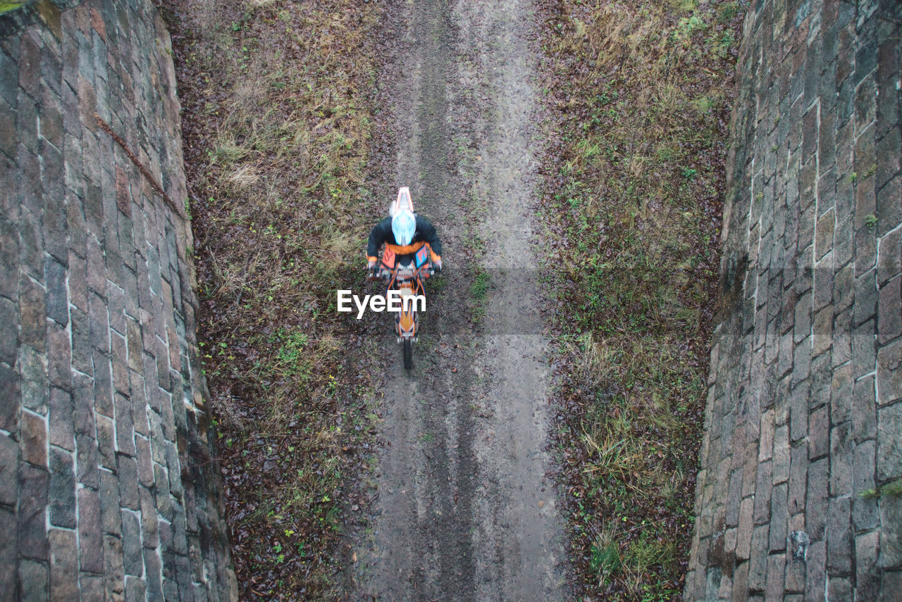 Directly above shot of person riding motorcycle on dirt road