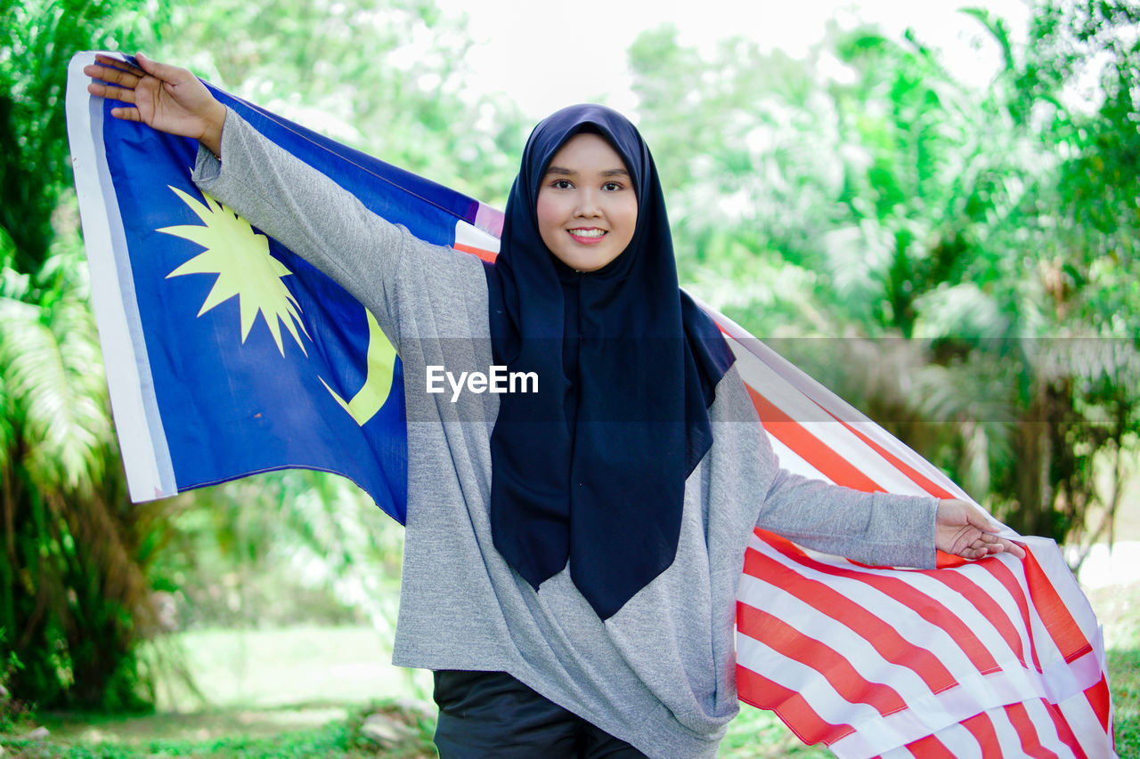 Muslim woman happy holding a malaysian flag. malaysia independence day.