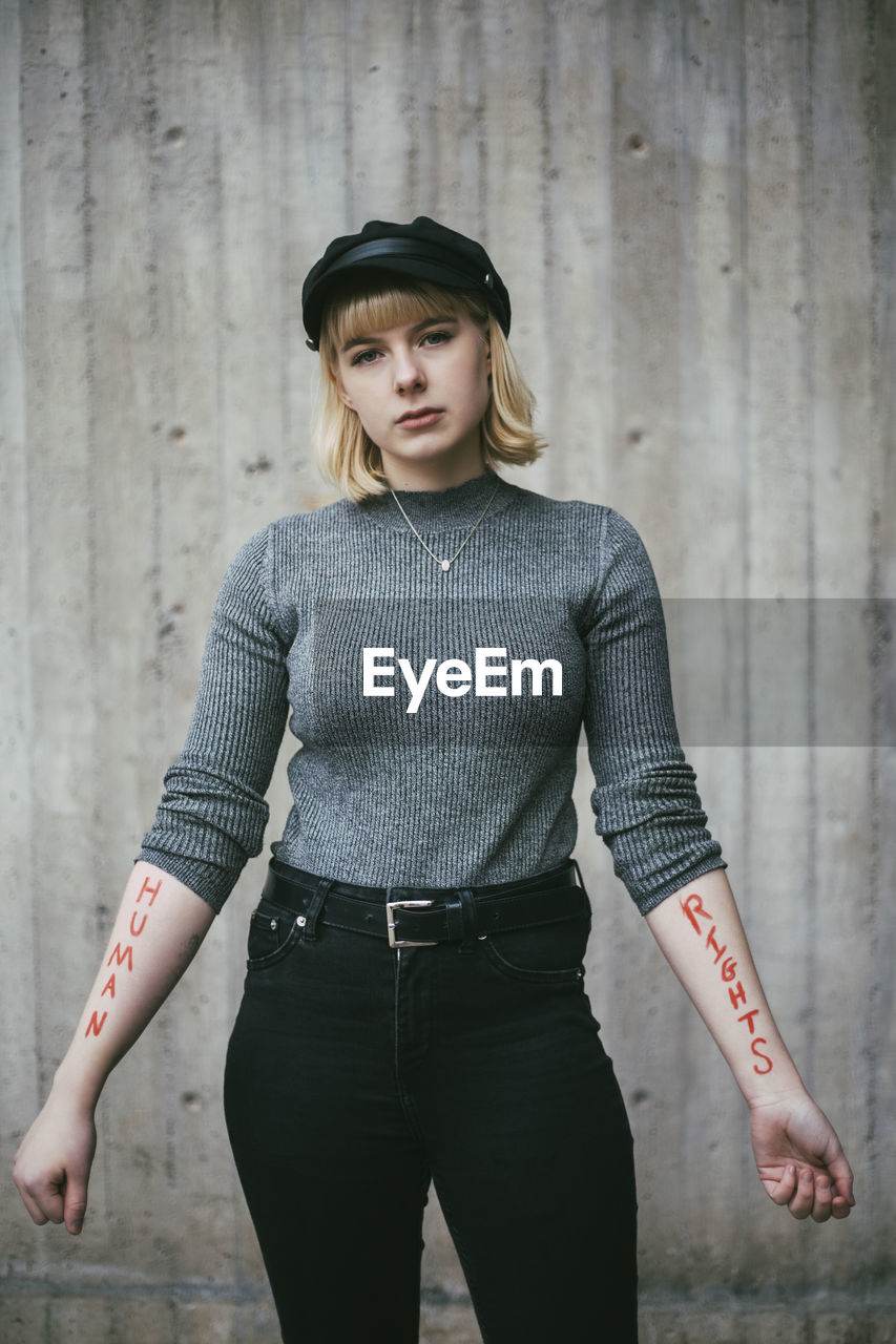 Portrait of female protestor showing equal rights written on hand against wall