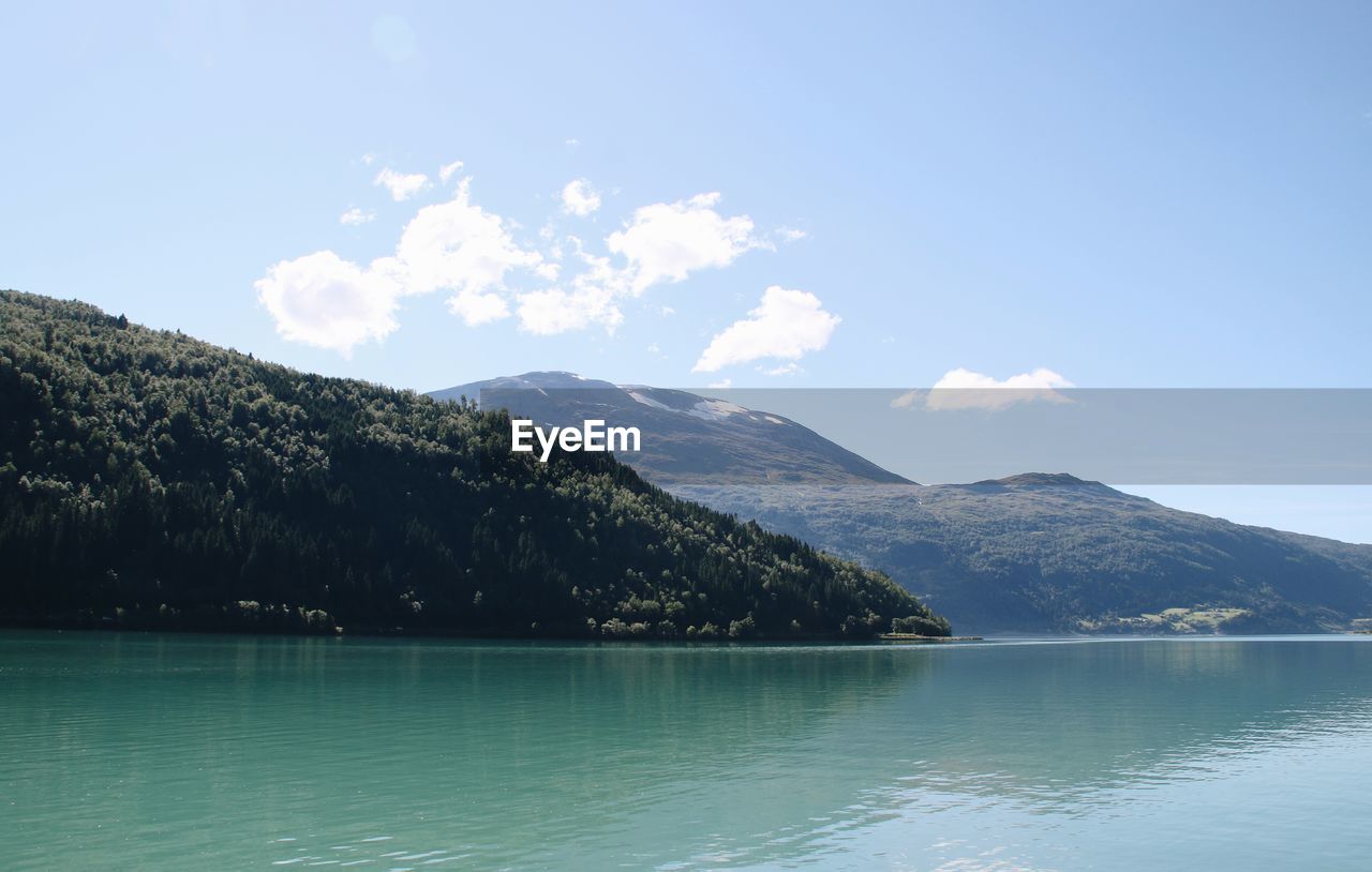 Scenic view of lake by mountains against sky