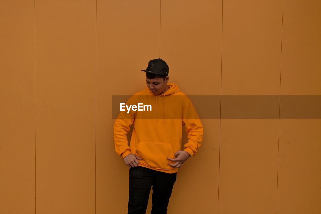 Young man standing against yellow wall