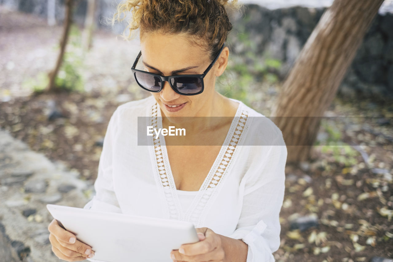 Close-up of woman using digital tablet while standing on field