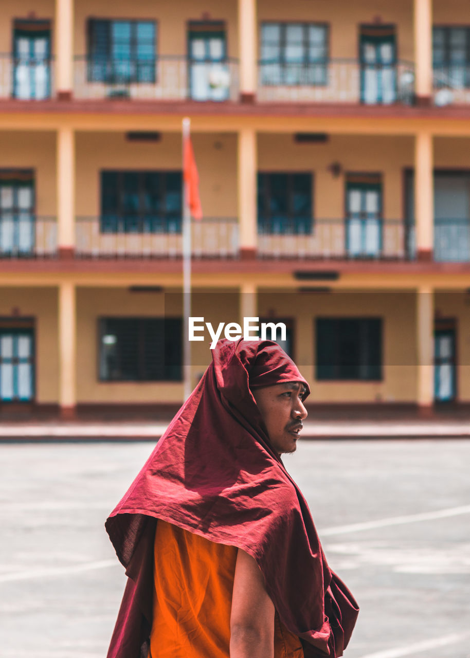 Monk standing against building