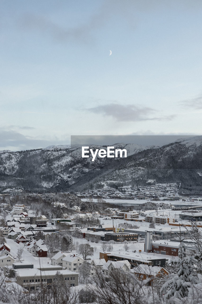 winter, snow, cold temperature, sky, scenics - nature, environment, architecture, landscape, nature, no people, built structure, mountain, building exterior, beauty in nature, building, cloud, tranquility, tranquil scene, day, house, outdoors, land, residential district, high angle view, non-urban scene, moon, mountain range