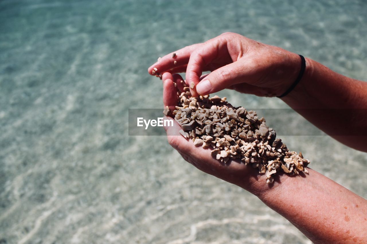 Cropped hand holding stones at beach