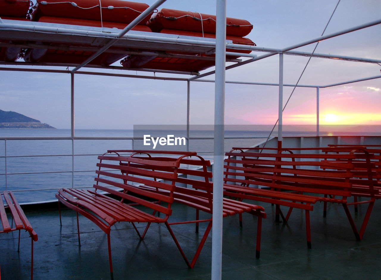 Boat deck at sunset with empty orange benches.