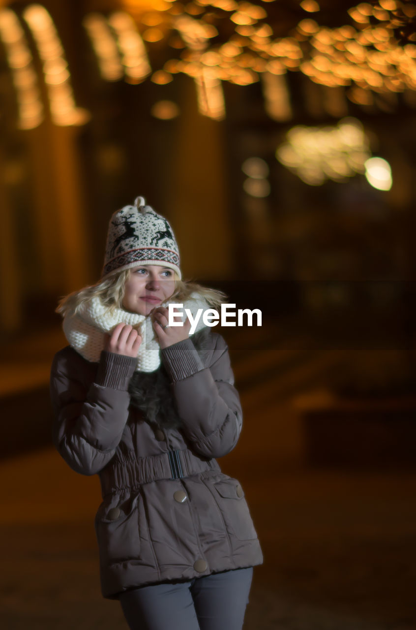 Woman standing on road in city at night