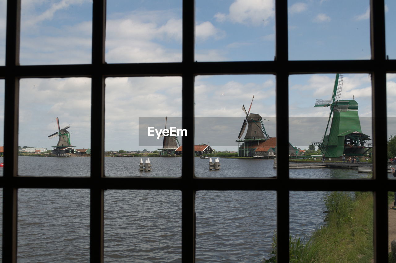 River in front of windmills seen through window