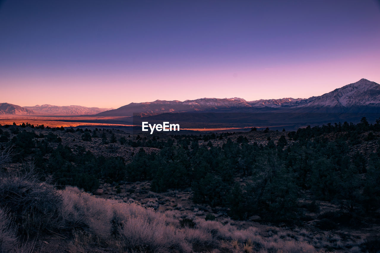 Scenic view of landscape against dramatic sky at sunset