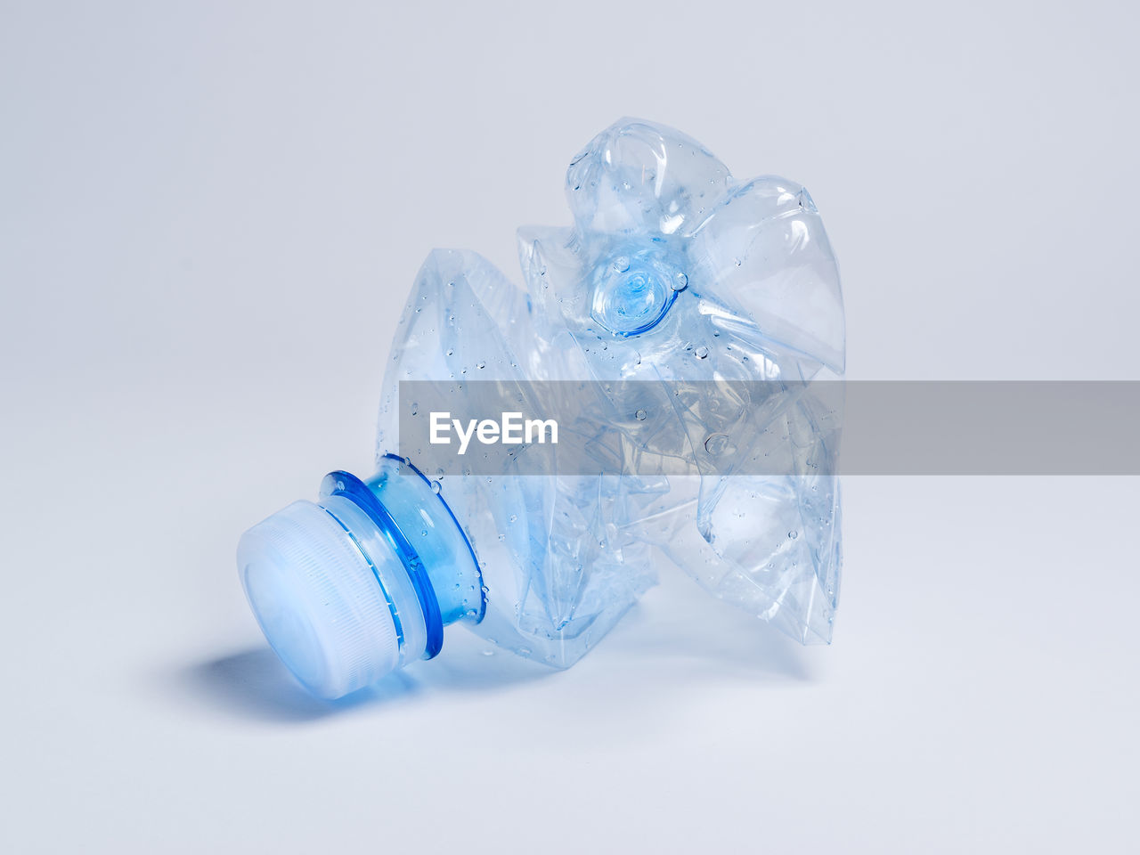Close-up of crumpled water bottle over white background
