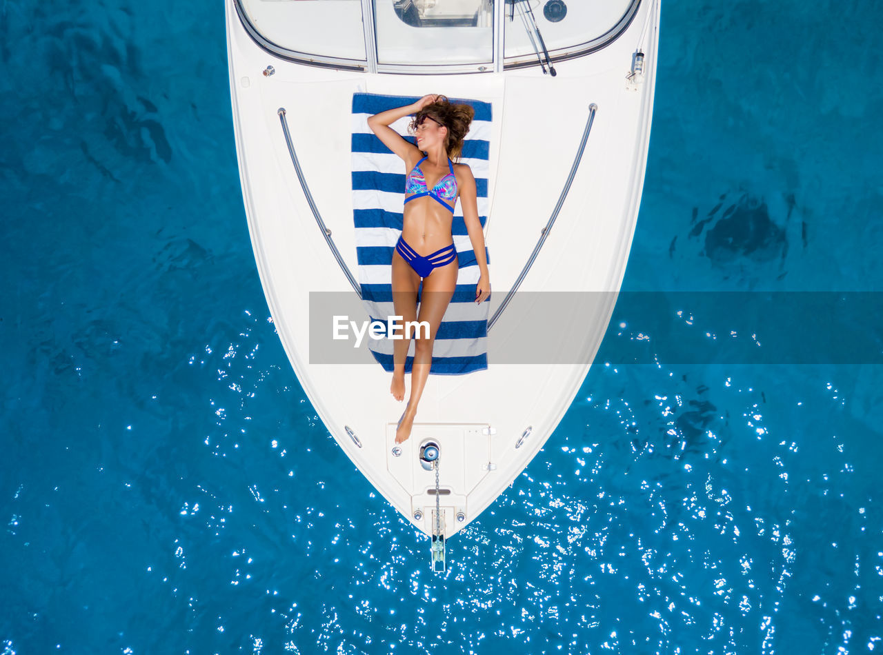 Directly above view of woman in bikini sunbathing on boat