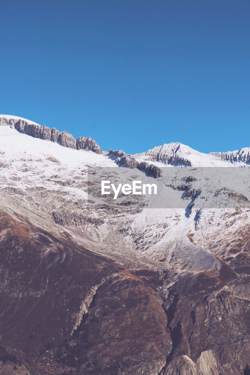 Scenic view of rocky mountains against clear sky during winter