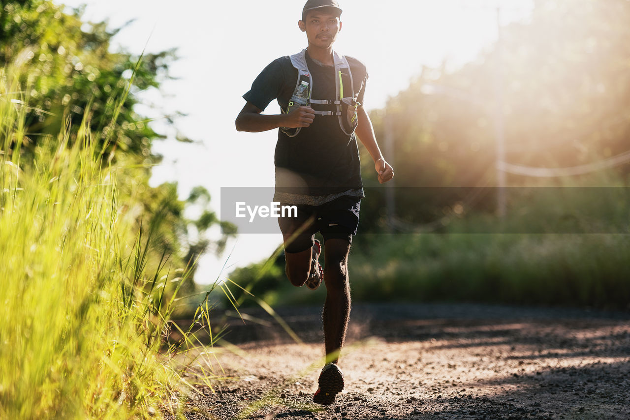 Full length of young man jogging on dirt road