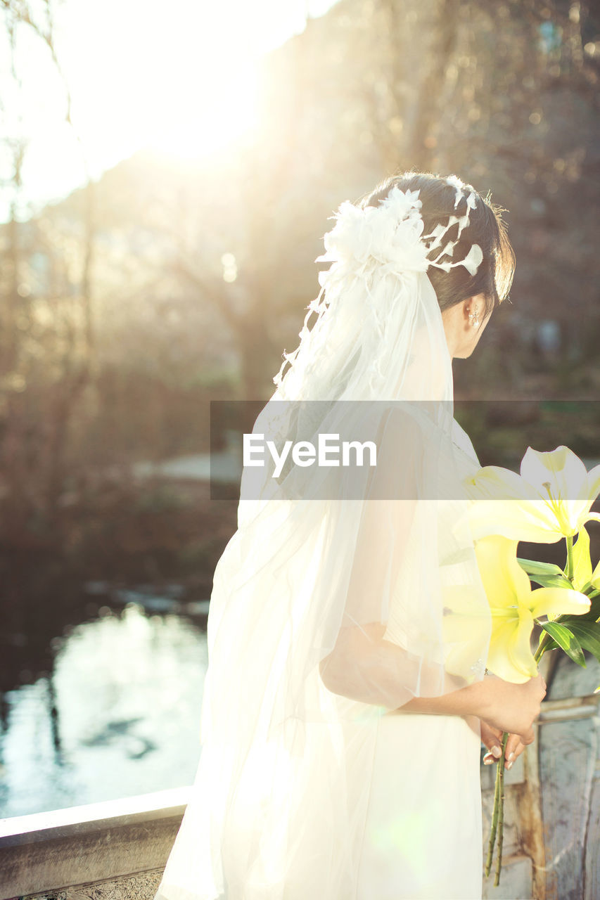 Side view of bride with bouquet during sunny day