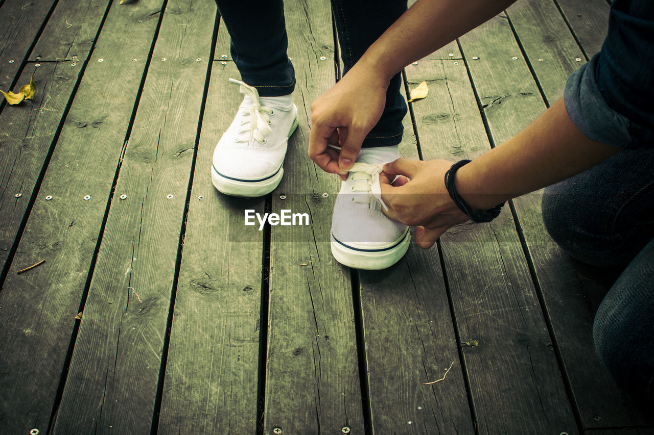 High angle view of man tying shoelace for friend