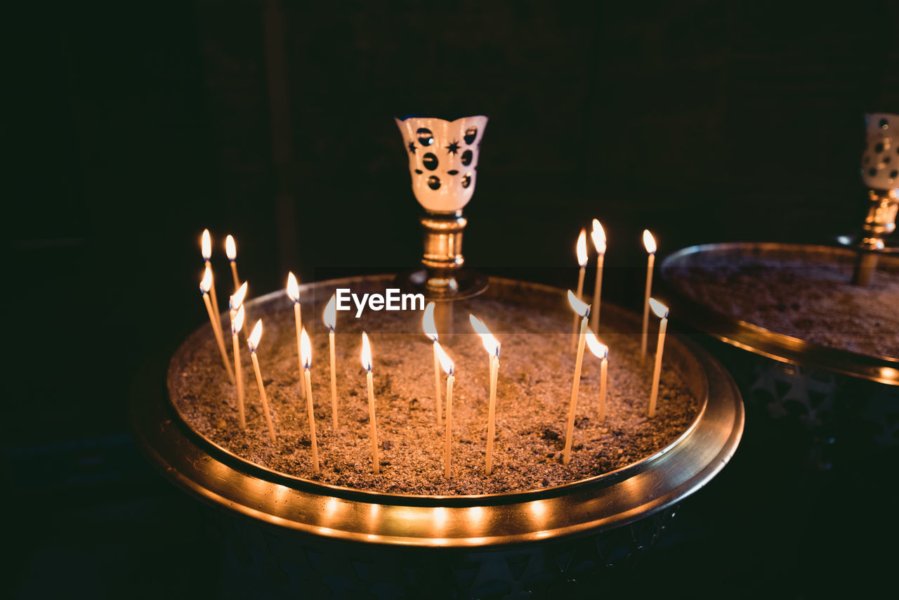 Close-up of lit candles in darkroom