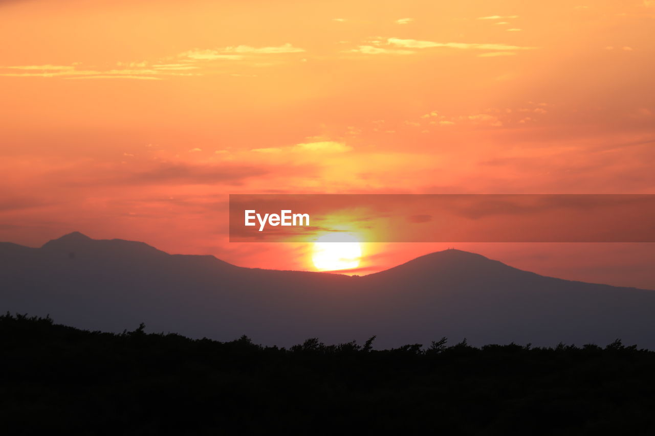 SCENIC VIEW OF SILHOUETTE MOUNTAINS AGAINST ORANGE SKY
