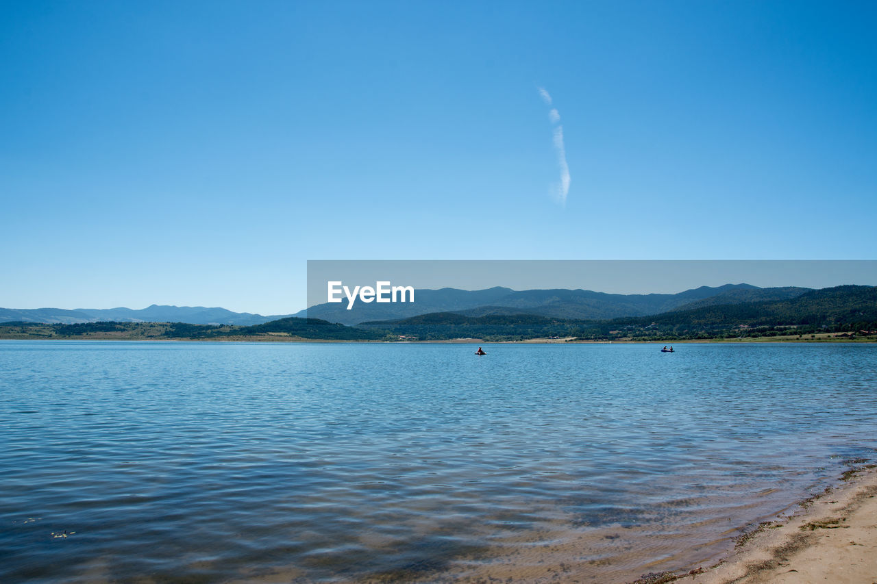 Scenic view of lake against clear blue sky