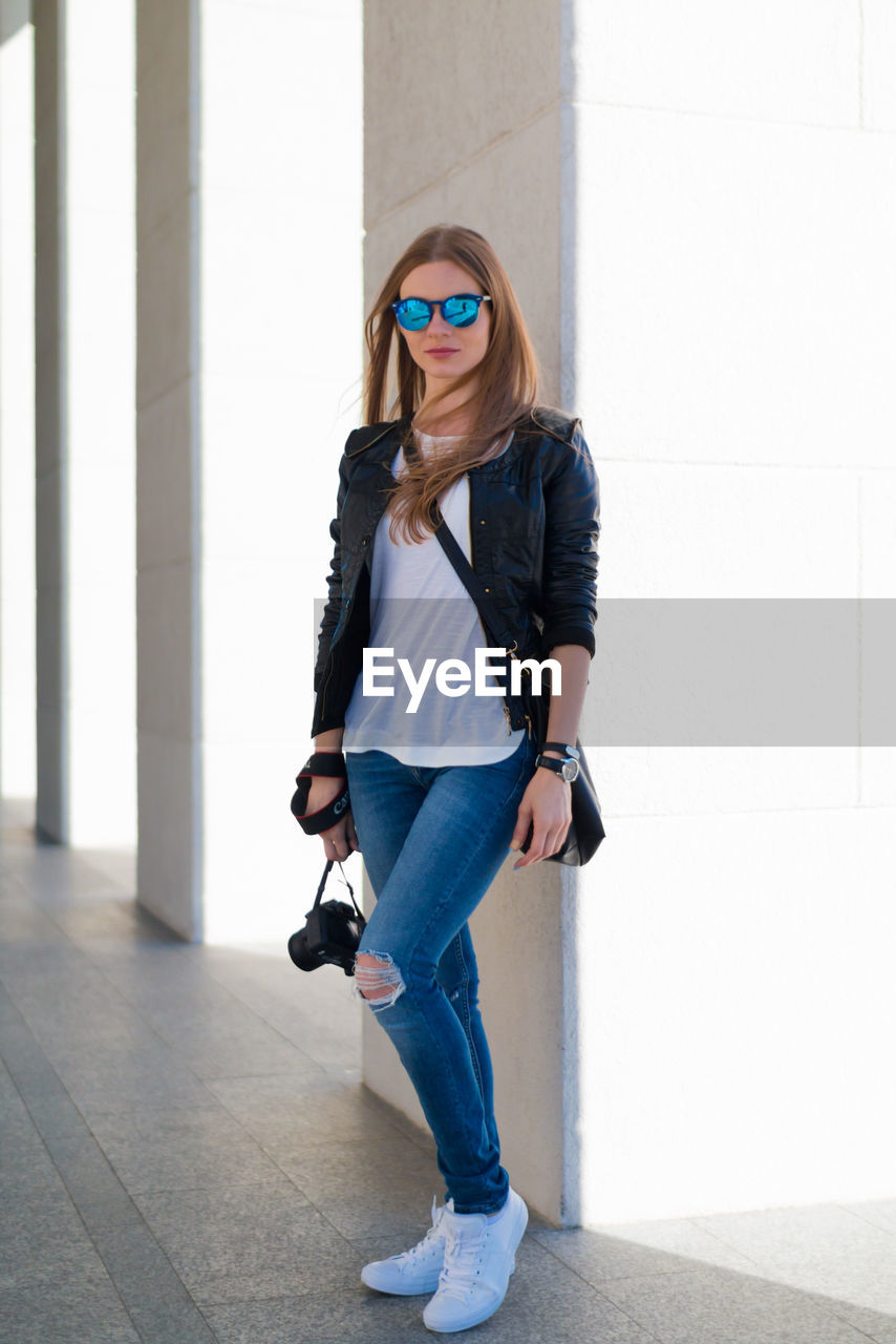 Portrait of young woman standing against columns