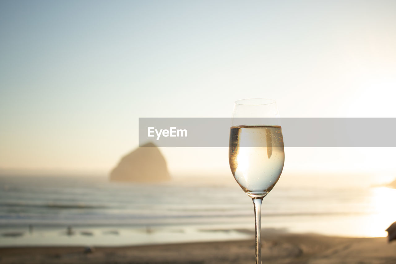 Close-up of champagne flute at beach against clear sky