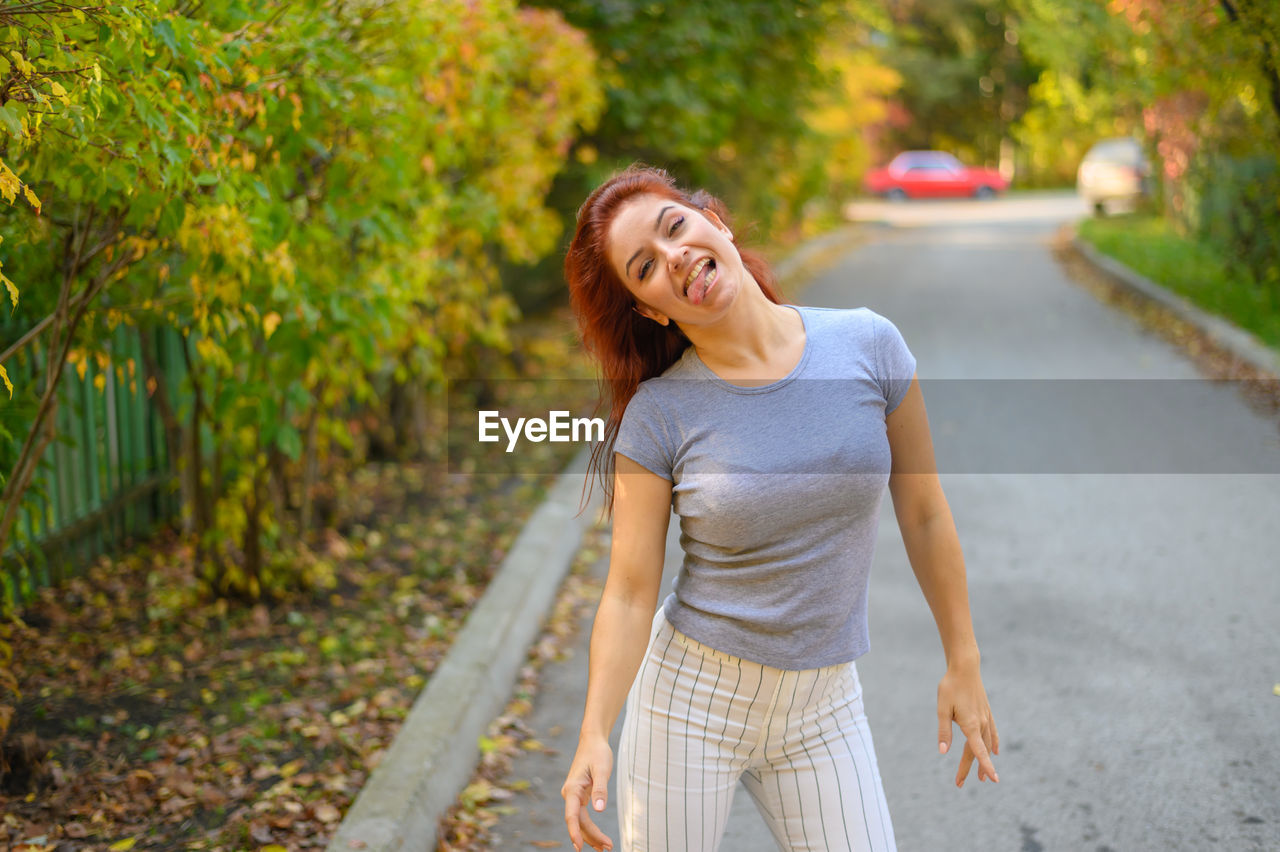 Portrait of smiling young woman standing on road