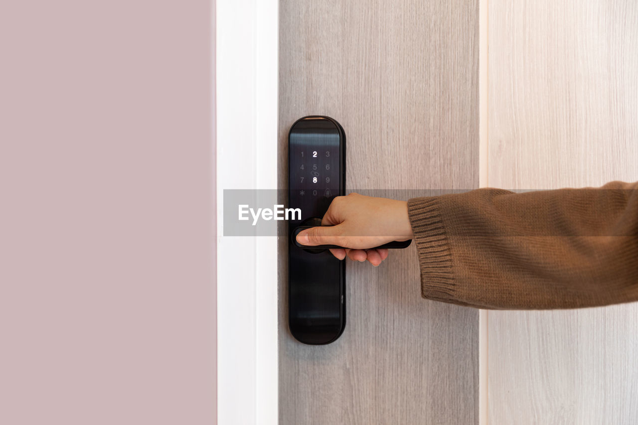 door, entrance, arm, technology, hand, one person, adult, communication, indoors, wireless technology, holding, clothing, business, copy space, men, portable information device, smartphone, brown, mobile phone