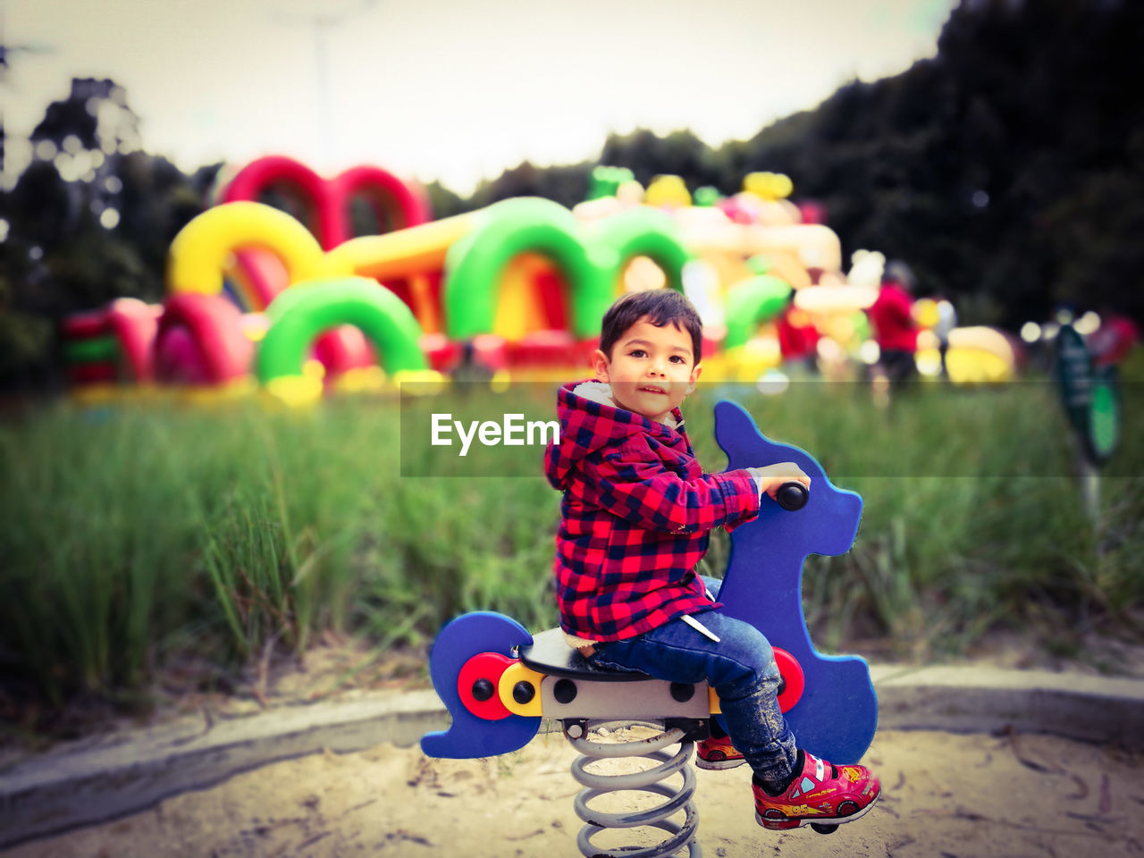 Side view of cute boy sitting on spring ride at playground