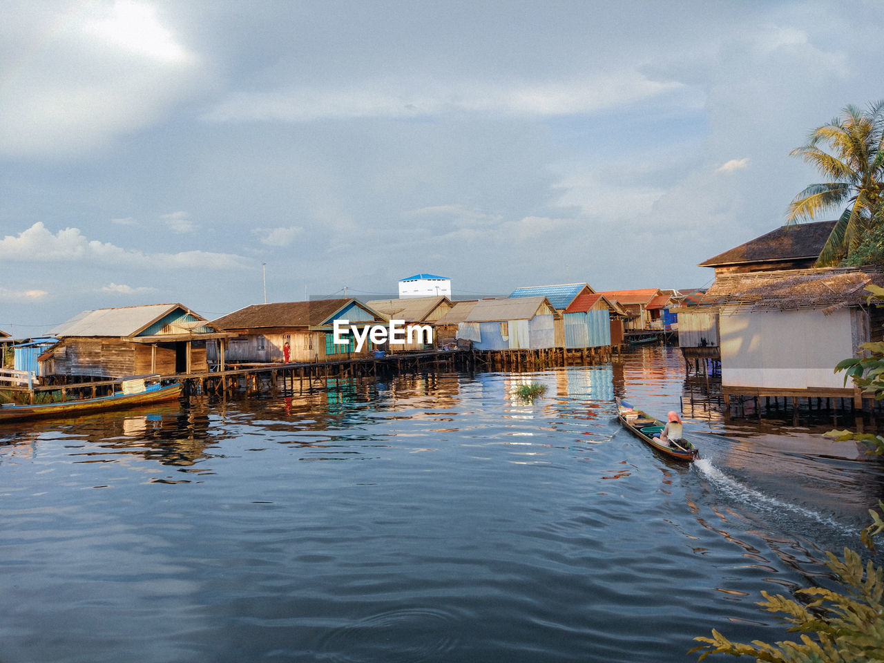 Stilt houses over lake against sky