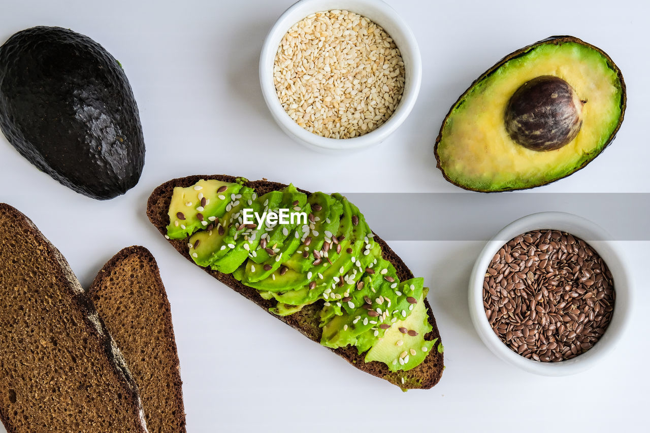 Ingredients for healthy avocado toast. ripe hass avocado, wholegrain bread, sesame flax seeds. vegan