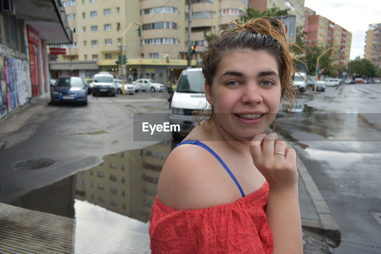 PORTRAIT OF SMILING YOUNG WOMAN IN CITY IN TOWN