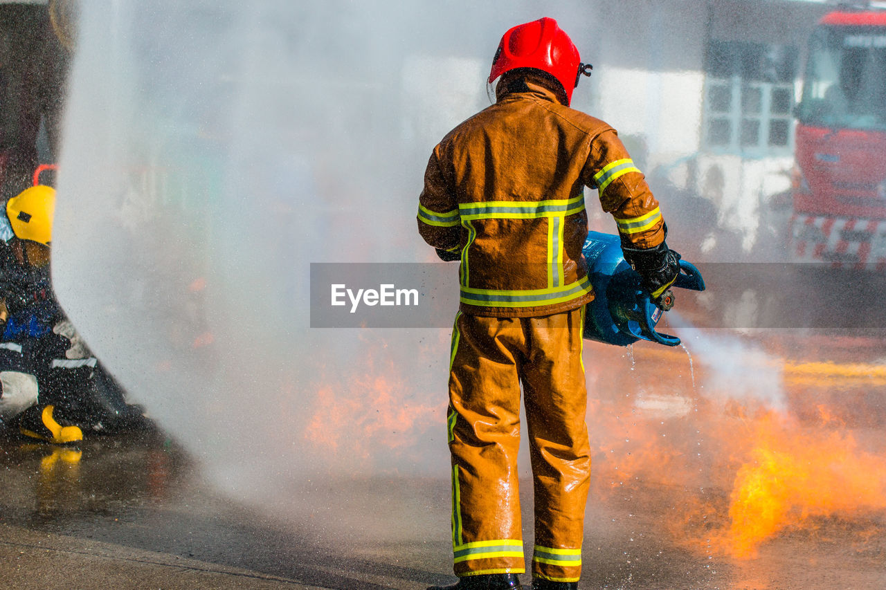 Rear view of firefighter extinguishing fire