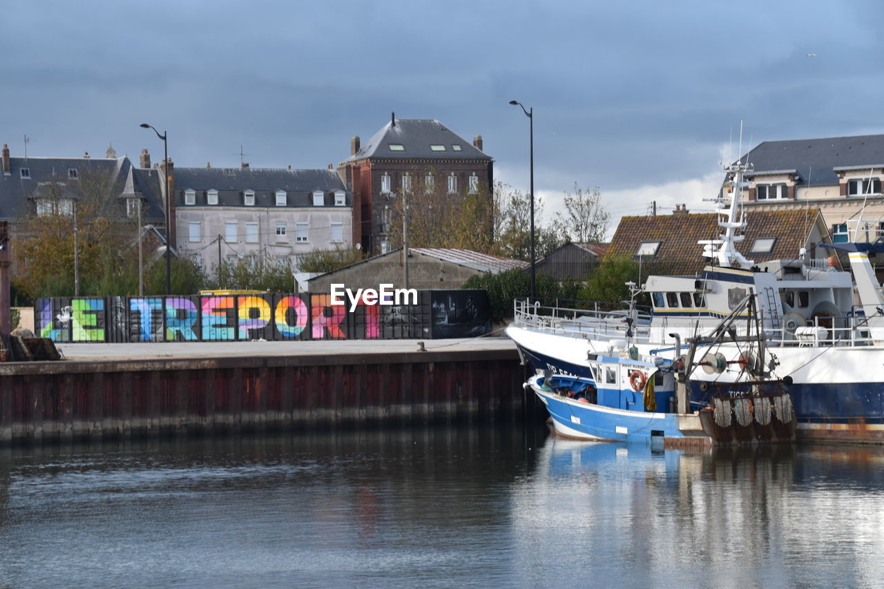 Boats moored at harbor against buildings in city