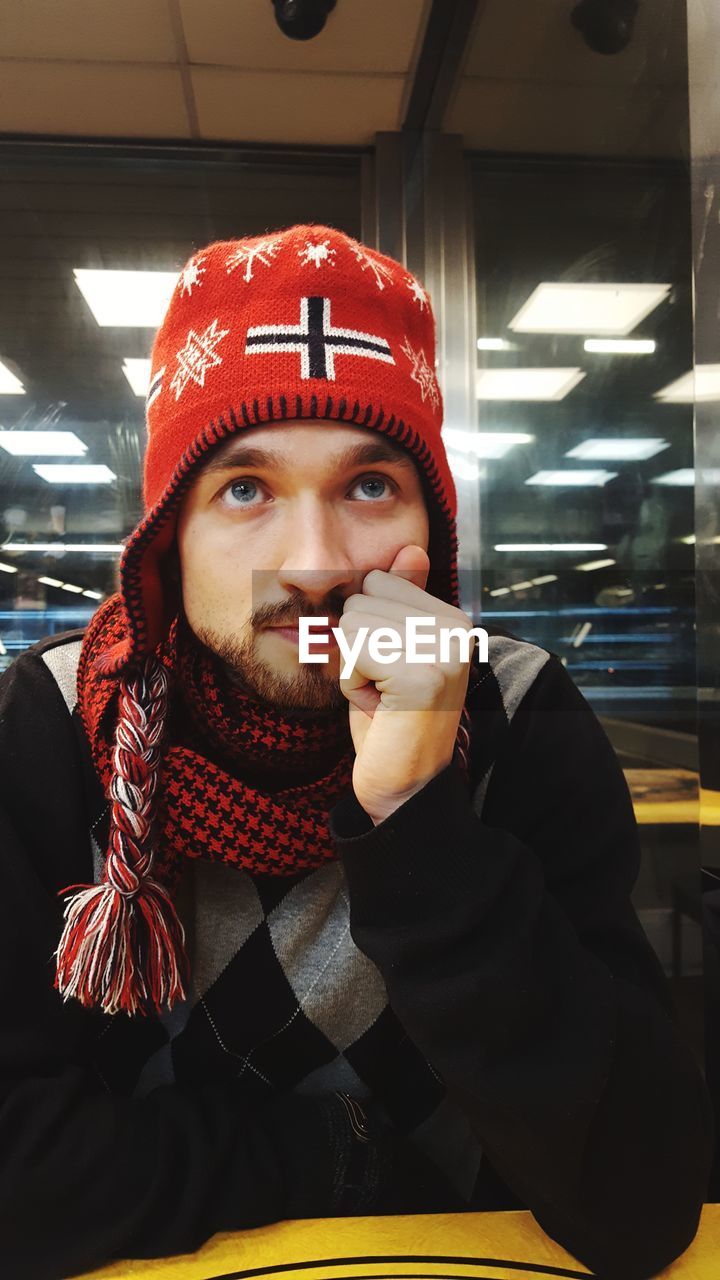 Portrait of young man sitting indoors in warm clothing