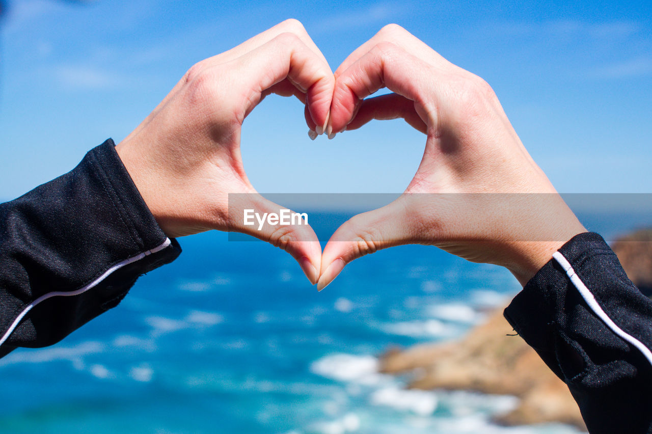 Close-up of hands holding heart shape against sky