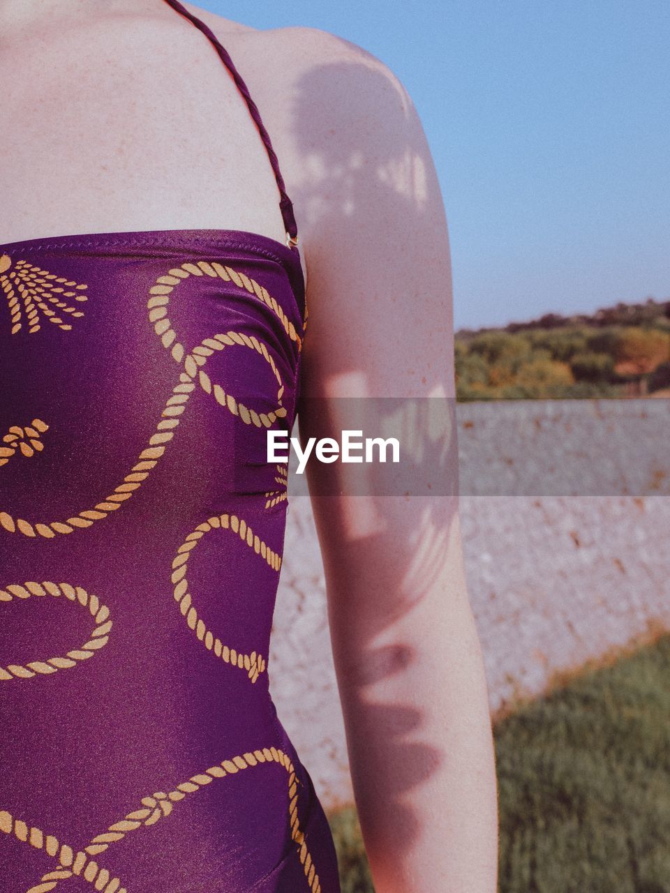 Midsection of woman wearing purple dress while standing against railing