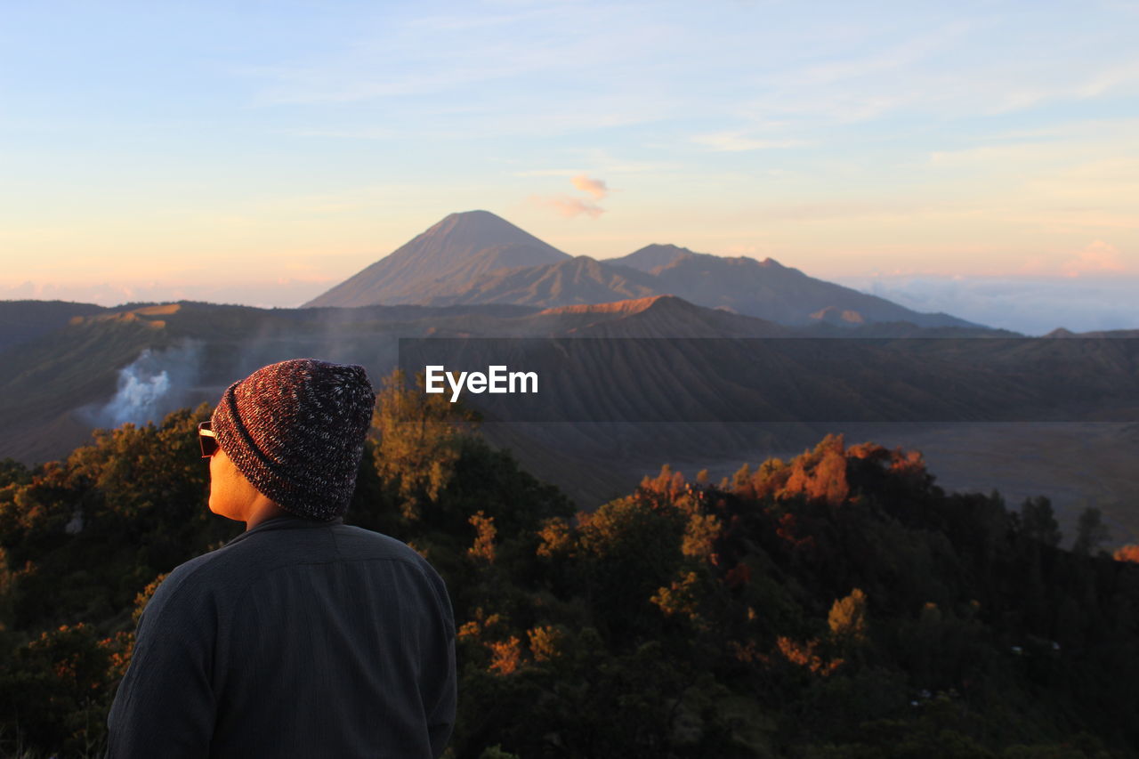 REAR VIEW OF MAN LOOKING AT MOUNTAINS