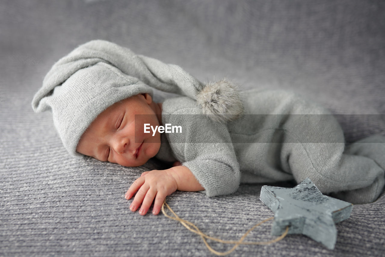 Cute newborn baby sleeping on gray blanket and holding craft wooden star. bed vibes.