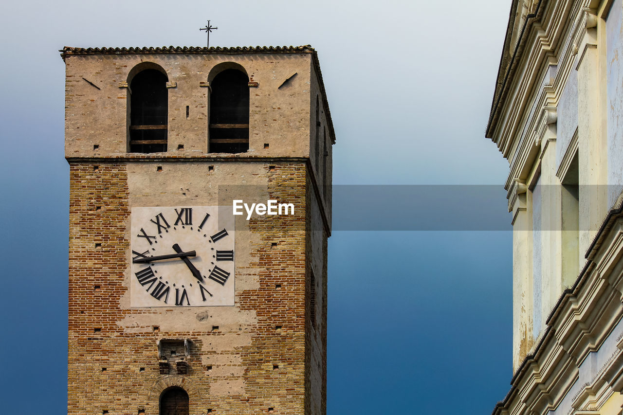 LOW ANGLE VIEW OF CLOCK TOWER AGAINST BUILDINGS