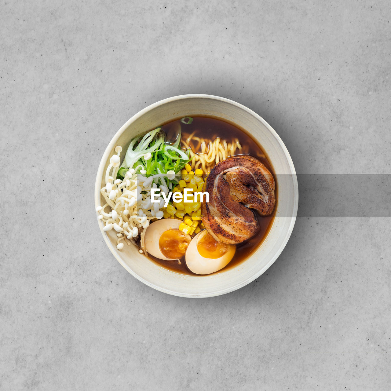 Asian noodle soup, ramen with meat, tofu, vegetables, enoki mushrooms and egg in black bowl
