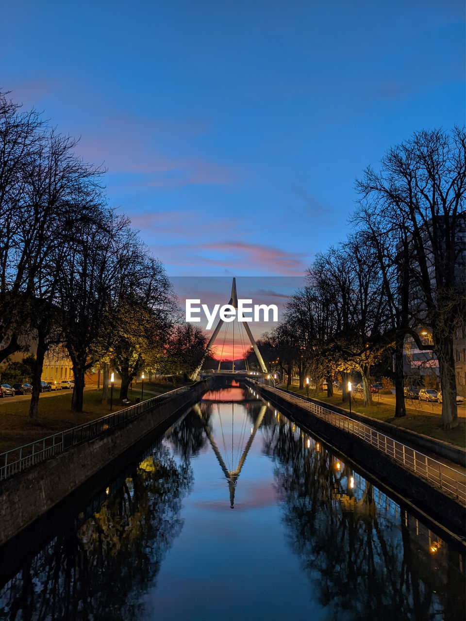 Canal amidst illuminated trees against sky at dusk ,mulhouse france