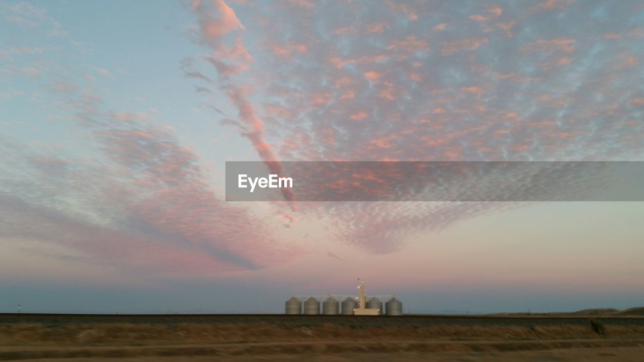 Landscape with silos in distance against sky