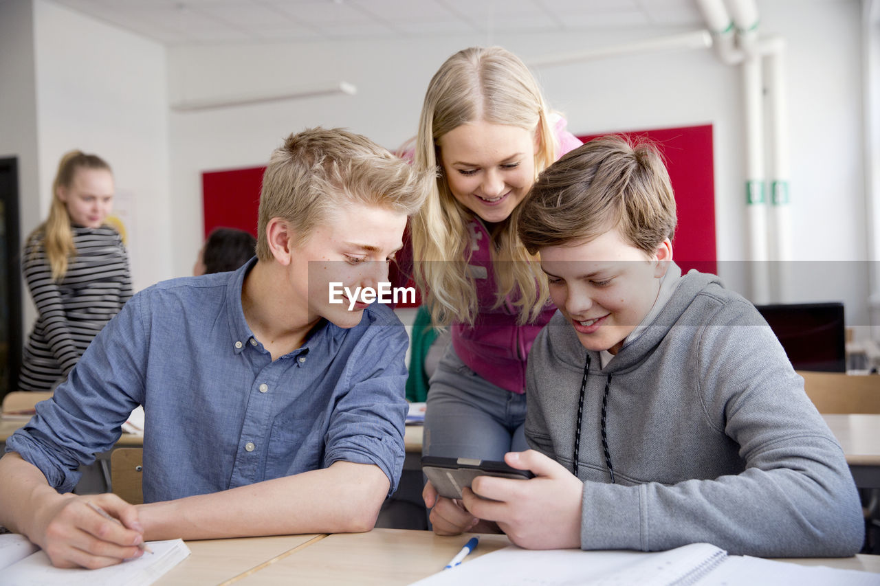 Teenagers looking at cell phone in classroom