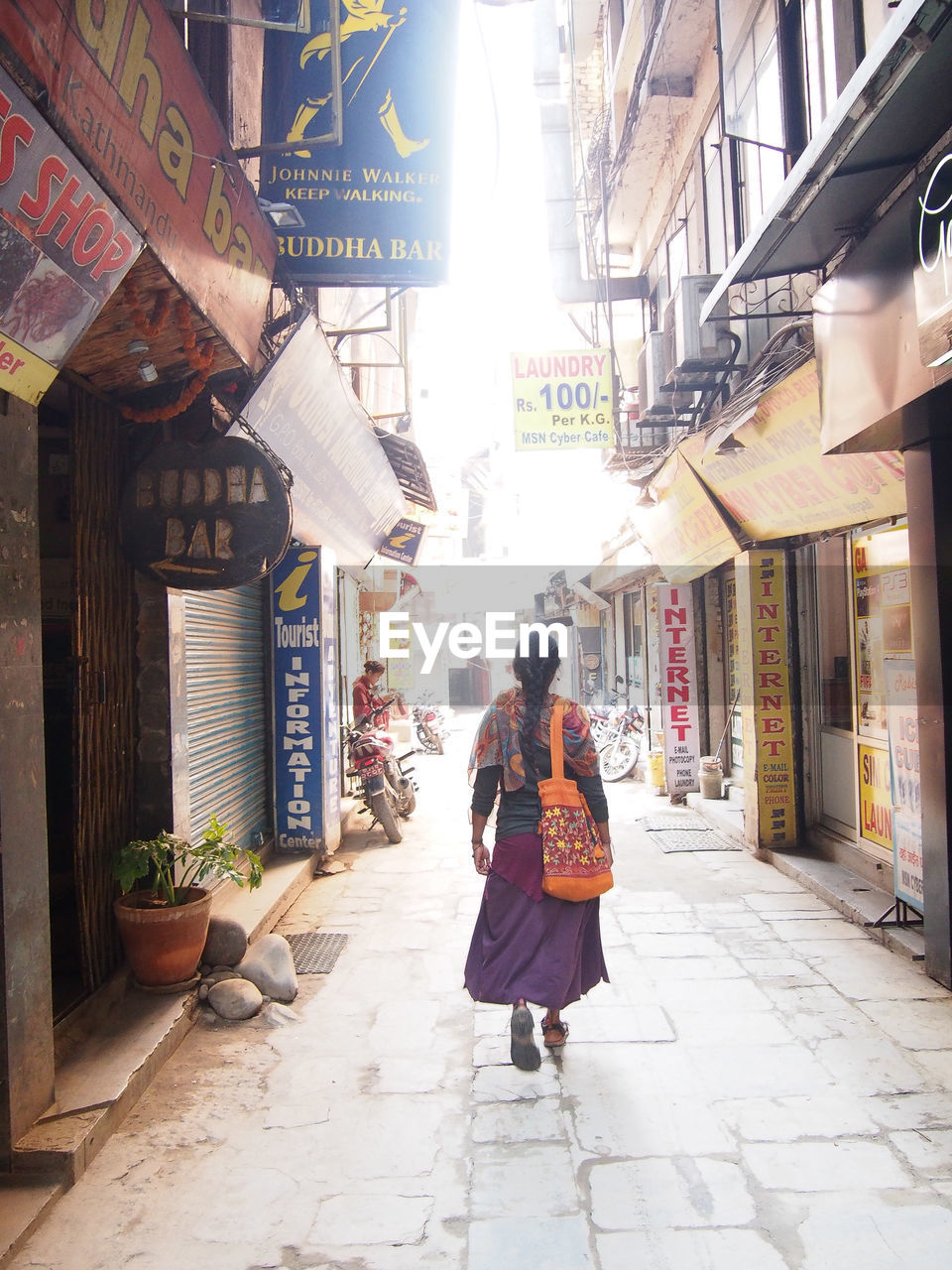 FULL LENGTH OF WOMAN WALKING ON STREET AMIDST CITY