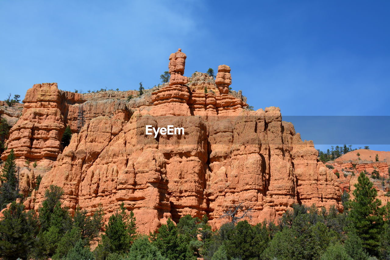 Low angle view of rocky mountain against blue sky