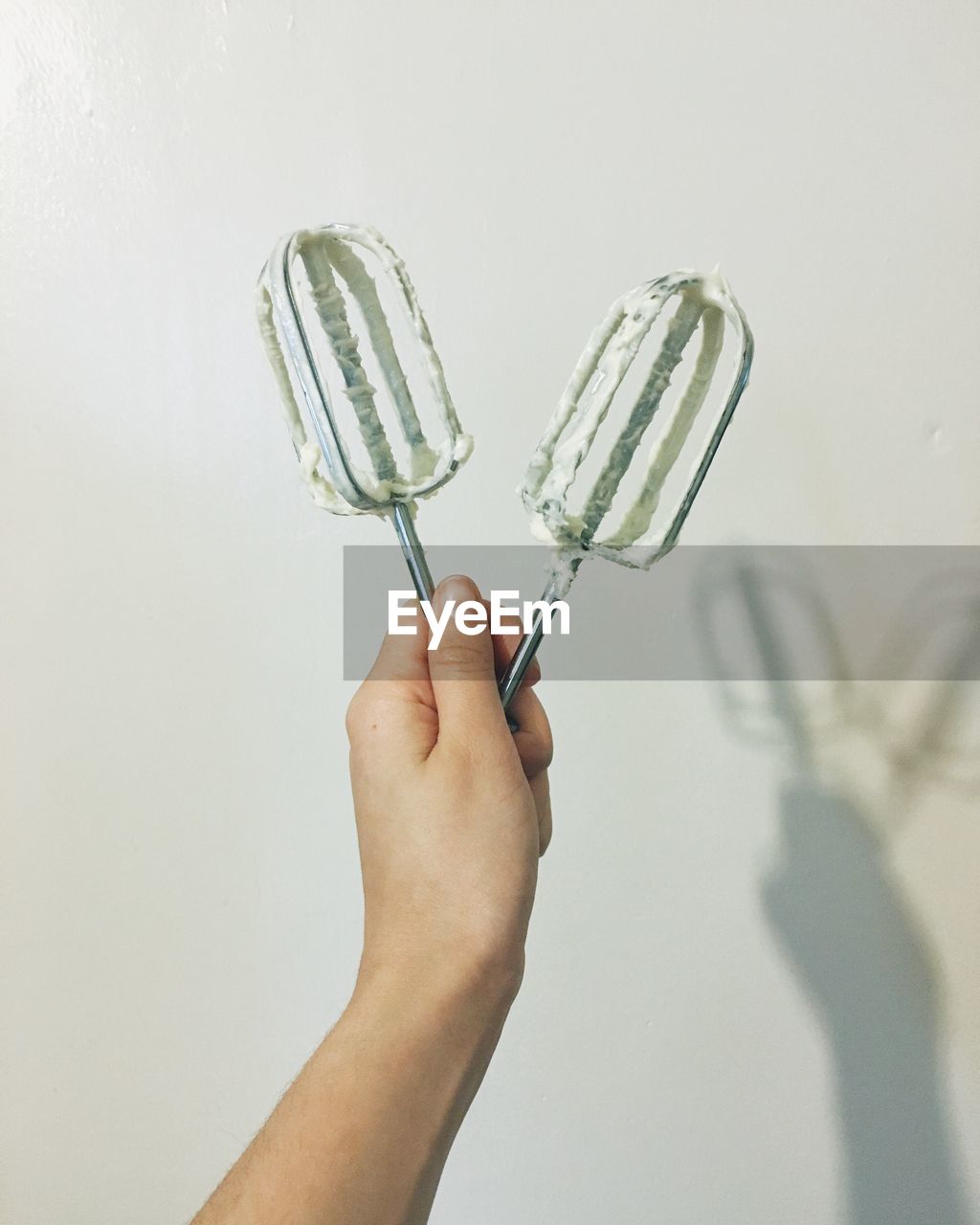 Cropped image of person holding ice candy against white background