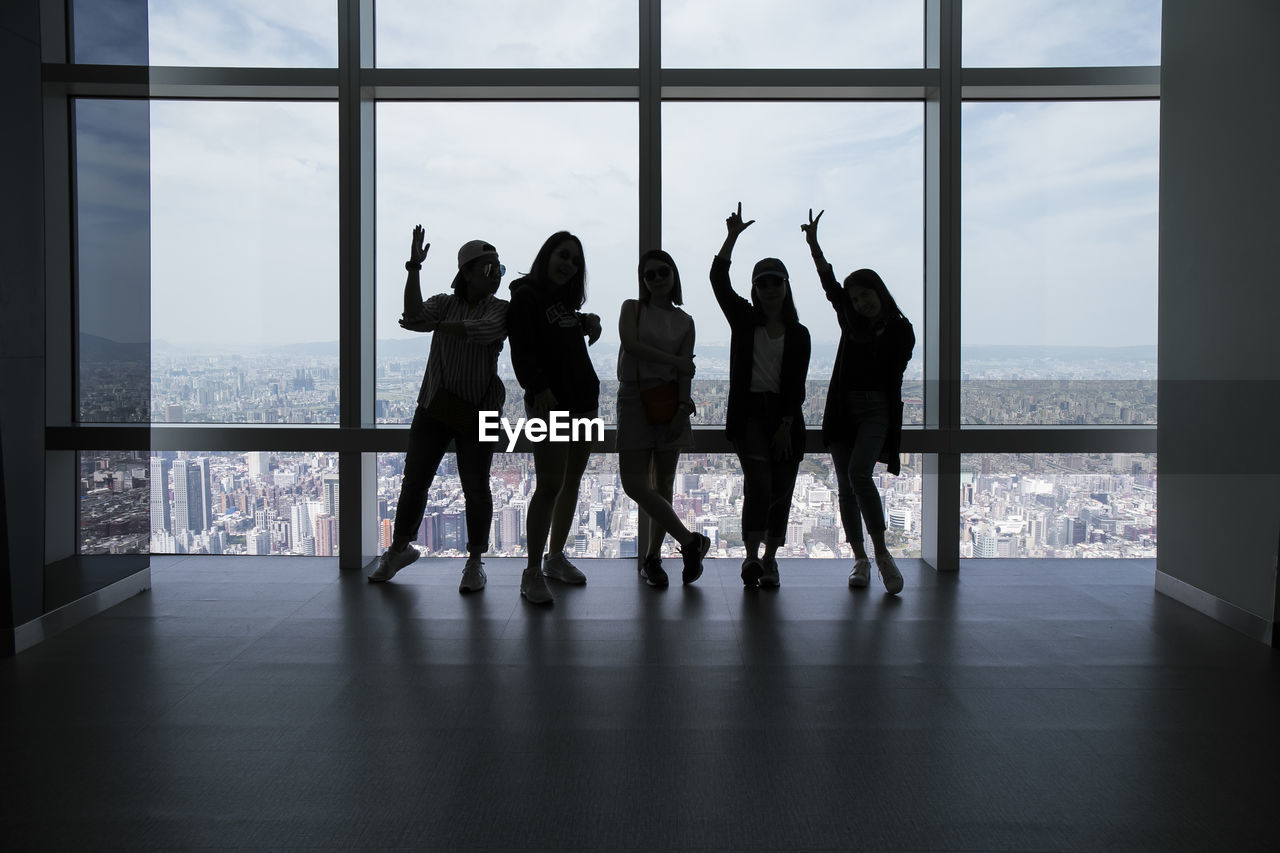 Friends sitting against window in building