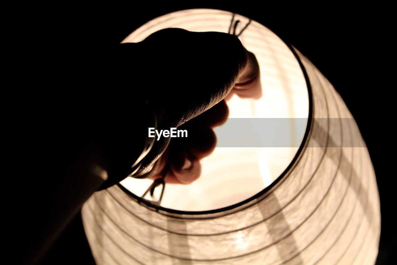 Cropped hand of person holding illuminated lantern