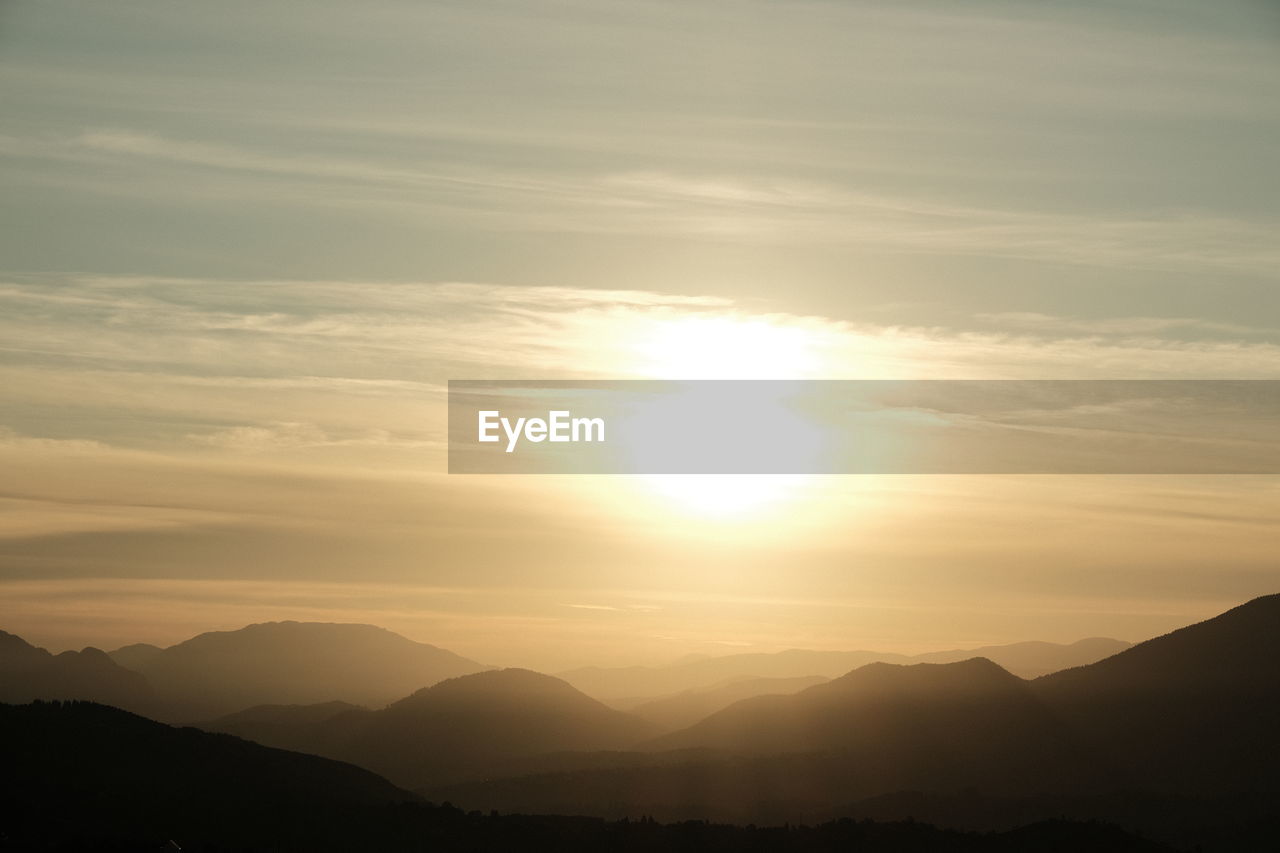 sky, mountain, beauty in nature, scenics - nature, sunset, tranquility, mountain range, sun, tranquil scene, environment, nature, sunlight, cloud, silhouette, landscape, dawn, idyllic, sunbeam, horizon, no people, non-urban scene, outdoors, dramatic sky, afterglow, back lit, lens flare, orange color, remote, awe